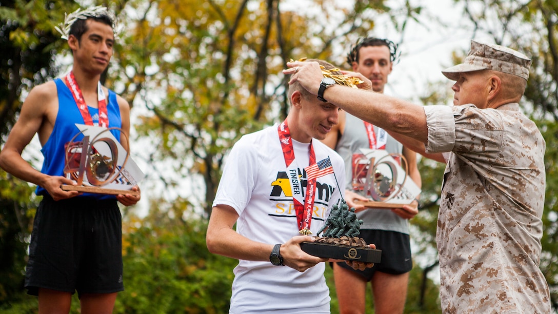 Gen. Robert Neller, the 37th Commandant of the Marine Corps, awards Trevor LaFontaine, the top male finisher of the 40th Marine Corps Marathon, his gold wreath in Arlington, Virginia, Oct. 25, 2015. The top three male and female finishers each received a medal, a trophy and a wreath, which was made in Marathon, Greece. This year’s participants joined the 512,370 runners, who have completed the “Marathon of the Monuments” since its inaugural event in 1976.