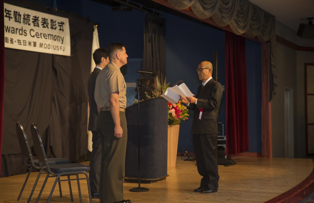 On behalf of the recipients, Sakae Hamada, right, translator with criminal investigation at the Provost Marshal’s Office, addresses Takahiro Sugawara, Director General, Chugoku – Shikoku Defense Bureau and Col. Robert V. Boucher, commanding officer of Marine Corps Air Station Iwakuni, Japan, at the Club Iwakuni ballroom Oct. 22, 2015. The Length of Service Award Ceremony recognizes the Japanese civilian’s dedication and passion while working on the installation. The ceremony gave attendees a sense of appreciation for their support and recognition as part of the team.