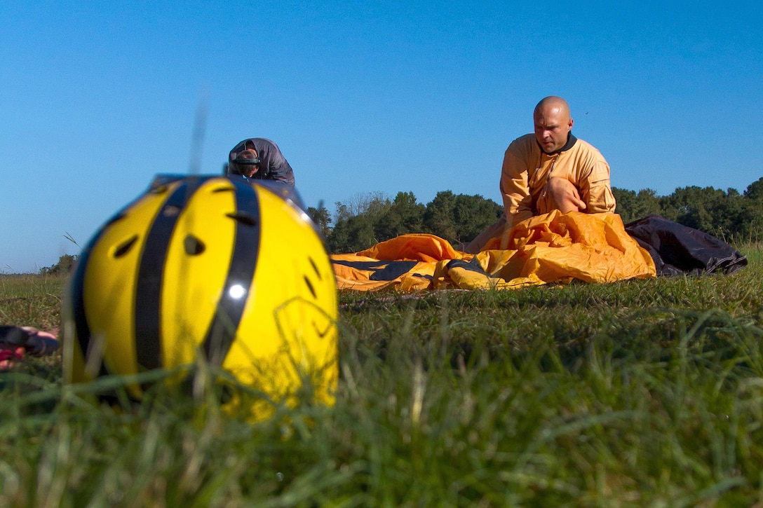 Army Sgt. 1st Class Sunnydale Hyde’s helmet sits on the ground as he repacks his parachute after performing a precision landing in Laurinburg, N.C., Oct. 20, 2015. He is a candidate trying out for the U.S. Army Parachute Team the Golden Knights. U.S. Army photo by Staff Sgt. David Meyer