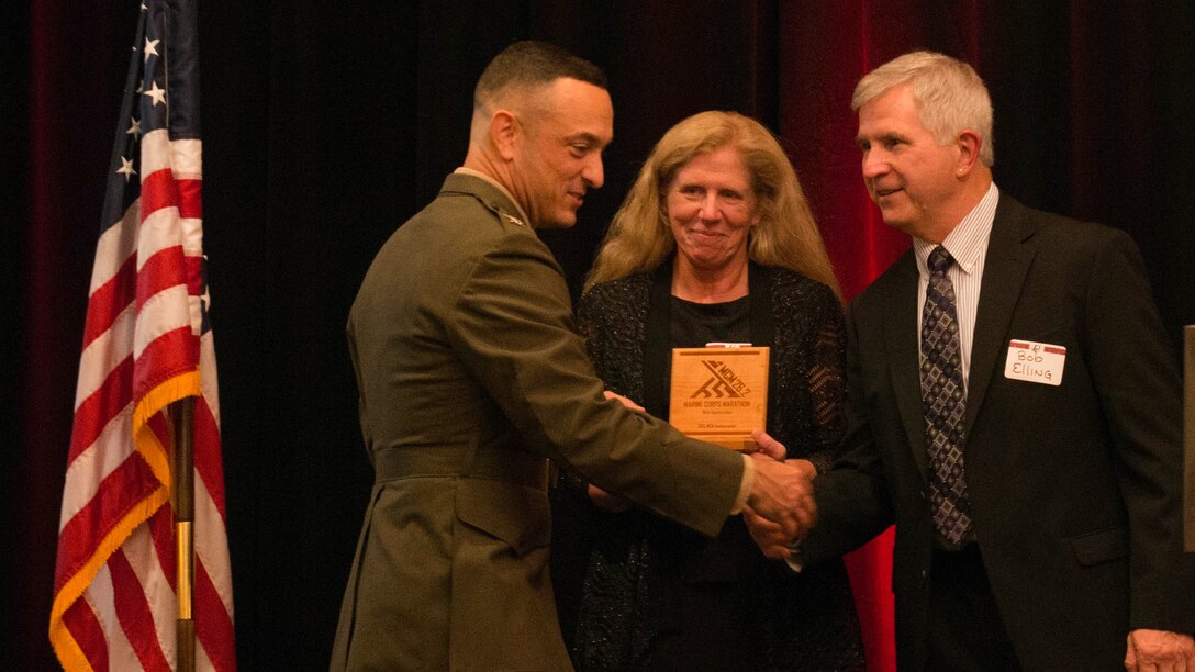 Col. Joseph M. Murray, commander, Marine Corps Installations National Capital Region-Marine Corps Base Quantico, presents Bob and Kirsten Elling with a plaque during the Marine Corps Hall of Fame dinner and ceremony at the Hyatt Regency Reagan National Airport in Crystal City, Va., Oct. 23, 2015. The Ellings were married at the start line of the 1996 MCM and have completed it annually ever since. They were given the title “ambassadors,” or individuals who have been apart of the marathon in interesting ways.