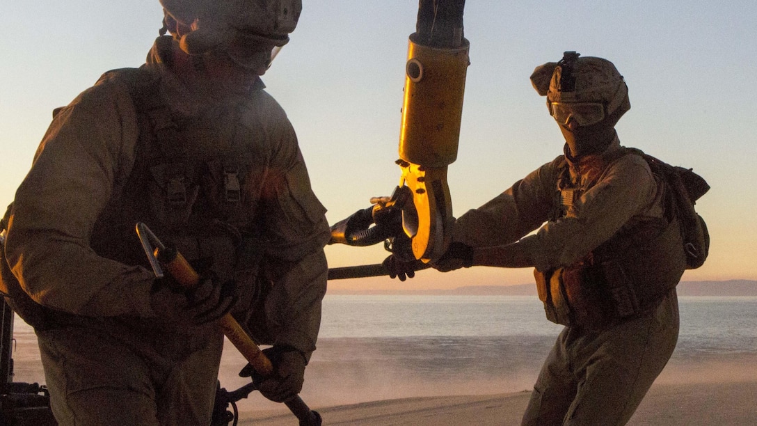 U.S. Marine Lance Cpl. Micah English, a landing support specialist with the Landing Support Detachment, 26th Marine Expeditionary Unit embarked aboard the amphibious transport dock ship USS Arlington (LPD 24) runs out from underneath a CH-53E Super Stallion with Marine Medium Tiltrotor Squadron (VMM) 162 (Reinforced), 26th MEU,  while U.S. Marine Lance Cpl. James Stamper, a landing support specialist, holds the connected sling during an external lift training exercise at Pinheiro Da Cruz, Praia Da Raposa Beach, Portugal, Oct. 22, 2015, during Trident Juncture 15. Trident Juncture is a NATO-led exercise designed to certify NATO response forces and develop interoperability among participating NATO and partner nations. 