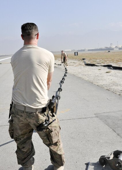 Staff Sgt. Timothy Shearer, 455th Expeditionary Civil Engineer Squadron, deployed from Shaw Air Force Base, S.C., works with Senior Airman Yves Meillarec, 455th ECES, deployed from Holloman AFB, N.M., on the aircraft arresting cable system Oct. 22, 2015, at Bagram Airfield, Afghanistan. Pilots will engage the arresting system during some precautionary landings to help slow or stop their aircraft. (U.S. Air Force photo by Tech. Sgt. Nicholas Rau/Released)