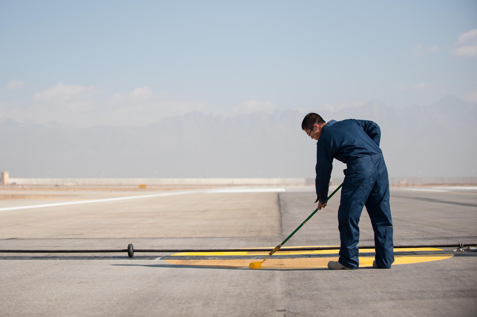 Airman 1st Class Elliot Oh, 455th Expeditionary Civil Engineer Squadron, paint runway markings Oct. 22, 2015, at Bagram Airfield, Afghanistan. The paint used is mixed with reflective beads to ensure that the markings can be seen by the pilots coming and going from Bagram in support of Operation Freedom’s Sentinel and NATO’s Resolute Support mission. (U.S. Air Force photo by Tech. Sgt. Joseph Swafford/Released)