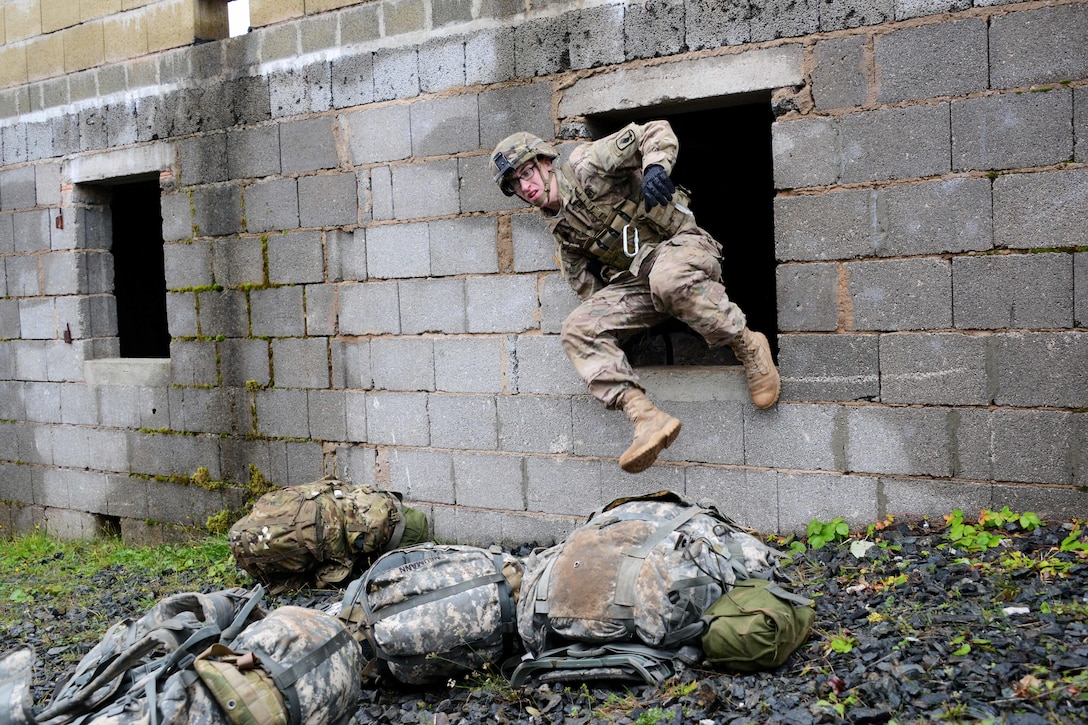 A U.S. soldier jumps through an open window during the urban casualty evacuation lane part of the European Best Squad Competition at the Grafenwoehr Training Area in Bavaria, Germany, Oct. 20, 2015. The soldier is assigned to the 173rd Airborne Brigade. U.S. Army photo by Gertrud Zach