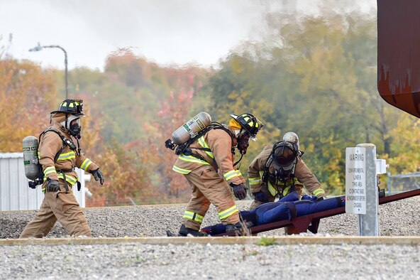 Members of the 910th Civil Engineer Squadron Fire Department remove a simulated victim from a blazing mock training aircraft during the second annual Feel the Heat event here, Oct. 22, 2015. Feel the Heat is an interactive training and demonstration event involving the 910th Airlift Wing and the American Red Cross Lake to River Chapter. During the event, the 910th Civil Engineer Squadron Fire Department ignited a mock training aircraft and responded with vehicles and personnel to combat the blaze and rescue victims. (U.S. Air Force photo/Eric M. White)
