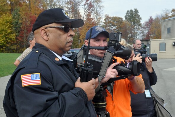 910th Airlift Wing Civil Engineer Fire Department Chief Tony Wells and members of the Youngstown-area media watch 910th firefighters respond to a controlled fire on a mock aircraft during the American Red Cross’ Feel the Heat event here, Oct. 22, 2015. The Feel the Heat emergency response capabilities exercise, observed by an audience of invited guests and area media representatives, showcased the partnership between the military and the Red Cross as part of the Air Force Community Partnership Program, which has been ongoing here since June 23, 2014. (U.S. Air Force photo/Master Sgt. Bob Barko Jr.)