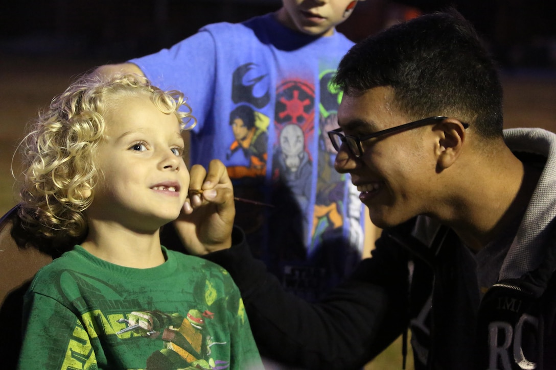 Jackson, a 6-year-old, smiles as Lance Cpl. Yoshio Galindo paints a design on his face during Fall Family Festival hosted by Marine Air Control Squadron 2 at Marine Corps Air Station Cherry Point, N.C., Oct. 22, 2015.  More than 100 Marines, Sailors and family members gathered to kick off the fall season with a chili cook-off and costume contest as well as games, a movie and a bonfire. Galindo is an aircraft maintenance administrative specialist. (U.S. Marine Corps photo by Cpl. N.W. Huertas/Released)