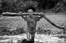 A competitor carries a large wooden log on her back through a mud pit during the Pensacola Mud Run Oct 24. Active duty and reserve service members from many local military bases came out to get dirty in the five-mile, 20-obstacle challenge.  (U.S. Air Force photo/Tech. Sgt. Sam King)