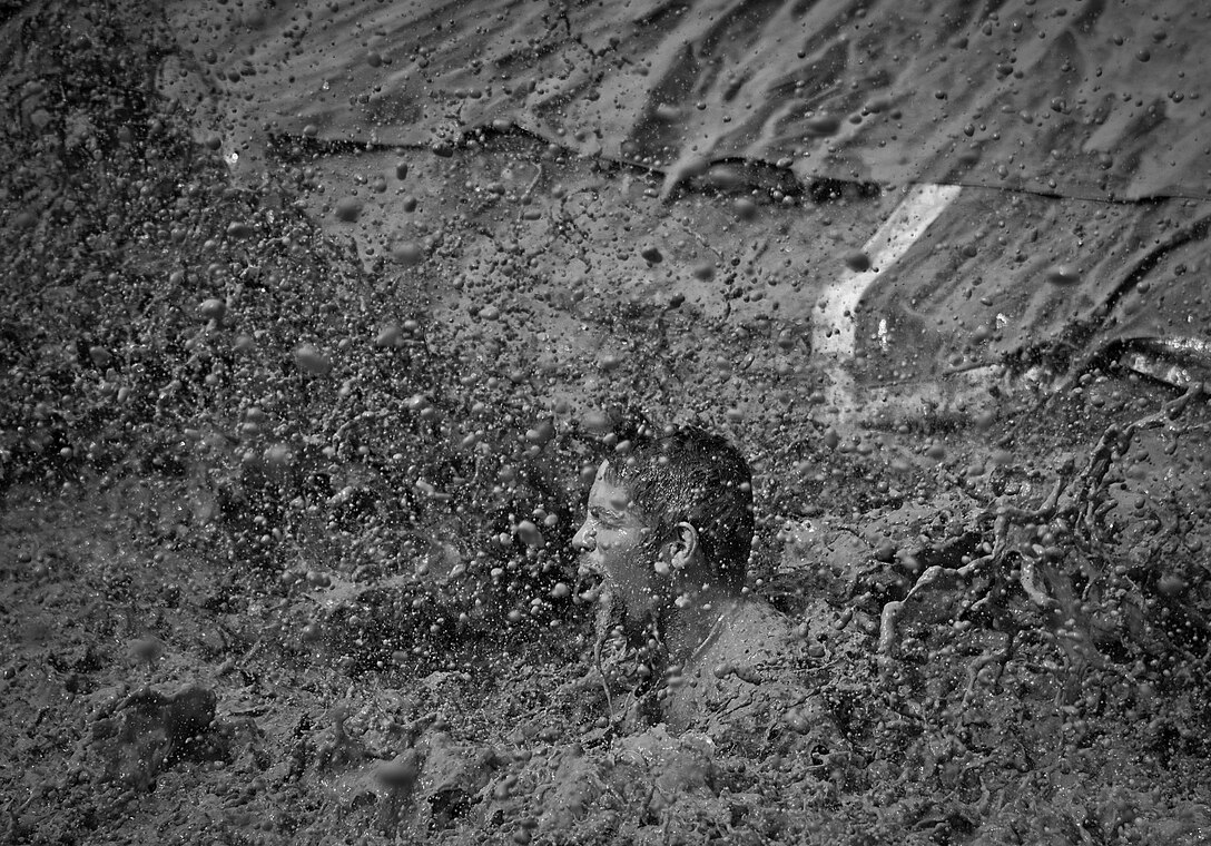 A competitor is enveloped by muddy water as he reaches the finish line via “mudslide” at the Pensacola Mud Run Oct 24. Active duty and reserve service members from many local military bases came out to get dirty in the five-mile, 20-obstacle challenge.  (U.S. Air Force photo/Tech. Sgt. Sam King)