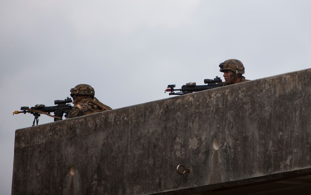Marines provide over watch security during a raid on Combat Town, at the Central Training Area, Okinawa, Japan, Oct. 26, 2015. The raid was part of Blue Chromite 2016, a large-scale amphibious exercise that achieves high-level training at a low cost, while keeping naval forces in a forward-deployed posture. During Blue Chromite, participating units take advantage of on-island training resources, saving in transportation and logistics cost. The Marines are with Alpha Company, 1st Battalion, 2nd Marine Regiment, currently assigned to 4th Marine Regiment, 3rd Marine Division, III Marine Expeditionary Force, under the unit deployment program. (U.S. Marine Corps Photo by LCpl. Steven Tran/Released)