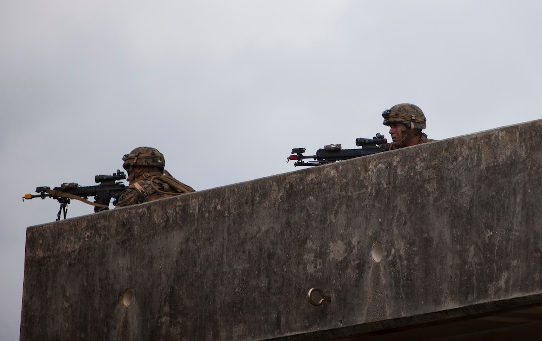 Marines provide over watch security during a raid on Combat Town, at the Central Training Area, Okinawa, Japan, Oct. 26, 2015. The raid was part of Blue Chromite 2016, a large-scale amphibious exercise that achieves high-level training at a low cost, while keeping naval forces in a forward-deployed posture. During Blue Chromite, participating units take advantage of on-island training resources, saving in transportation and logistics cost. The Marines are with Alpha Company, 1st Battalion, 2nd Marine Regiment, currently assigned to 4th Marine Regiment, 3rd Marine Division, III Marine Expeditionary Force, under the unit deployment program. (U.S. Marine Corps Photo by LCpl. Steven Tran/Released)