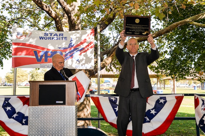 Dr. Dave Hansen, 309th Electronics Maintenance Group director, holds aloft the commemorative plaque, presented by Brad Baptiste, left, designating the unit as a Voluntary Protection Program Star status site. Baptiste is the regional VPP manger from the Denver Department of Labor office, and led the evaluation team that recommended the unit be designated as a Star worksite. (U.S. Air Force photo by R. Nial Bradshaw)
