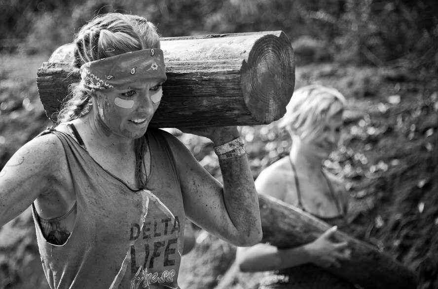 A competitor carries a wooden log through a mud pit during the Pensacola Mud Run Oct 24. Active duty and reserve service members from many local military bases came out to get dirty in the five-mile, 20-obstacle challenge.  (U.S. Air Force photo/Tech. Sgt. Sam King)