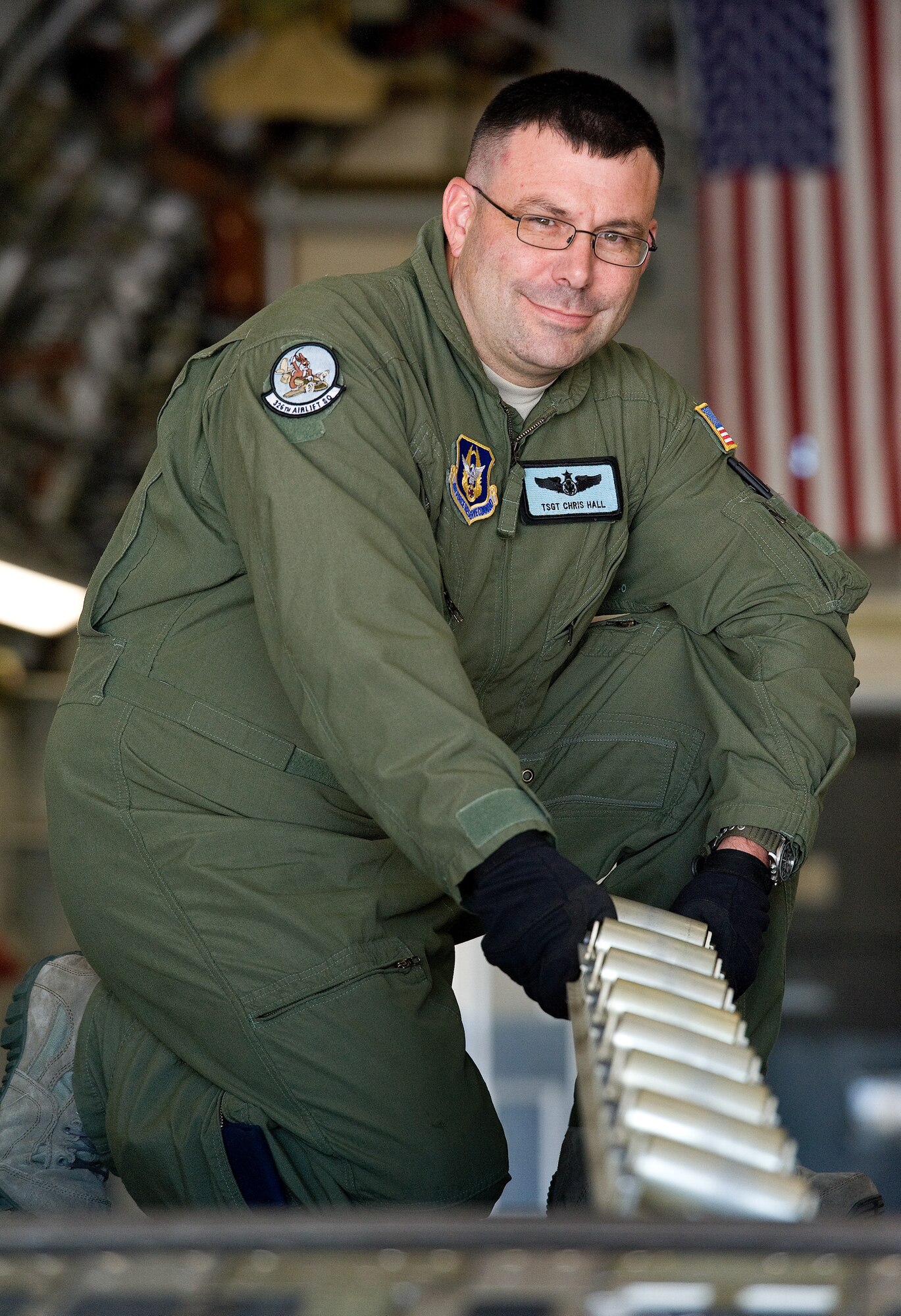 Tech. Sgt. Christopher Hall, 326th Airlift Squadron C-17 Globemaster III loadmaster instructor, poses for a photo while flipping rollers in the aircraft's cargo compartment Oct. 16, 2015, on Dover Air Force Base, Del. Hall, currently acting as a loadmaster scheduler, was randomly selected for The Airlifter's feature A face of Team Dover 2015: Vol. 2, No. 4. (U.S. Air Force photo/Roland Balik)