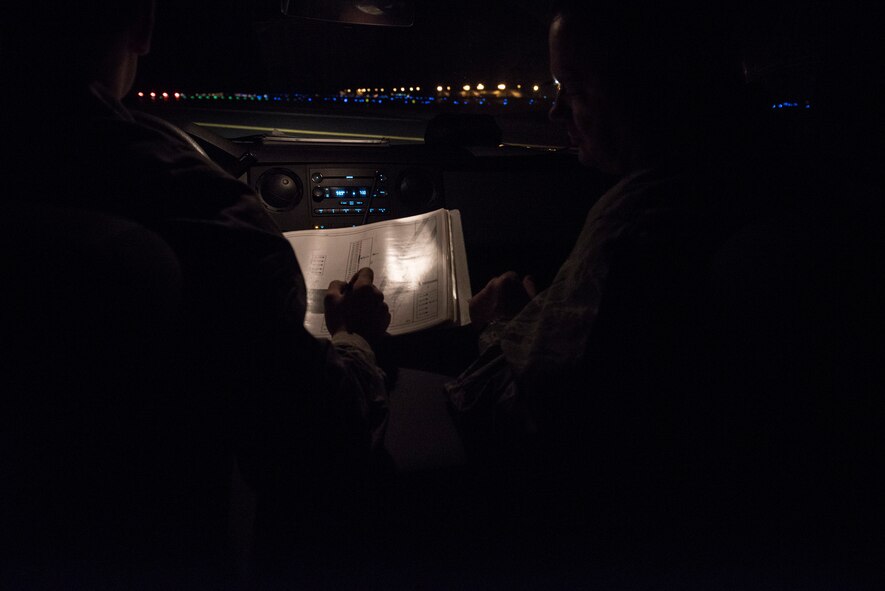 Col. Brian McDaniel, 92nd Air Refueling Wing commander, looks on as Airman 1st Class Hunter Lester, 92nd Operations Support Squadron airfield management apprentice, annotates a burnt out light Oct. 20, 2015, at Fairchild Air Force Base, Wash. The 92nd OSS airfield management night-shift team conducts a check of all the lights on the airfield, to include taxiways, every two hours. (U.S. Air Force photo/Airman 1st Class Sean Campbell)