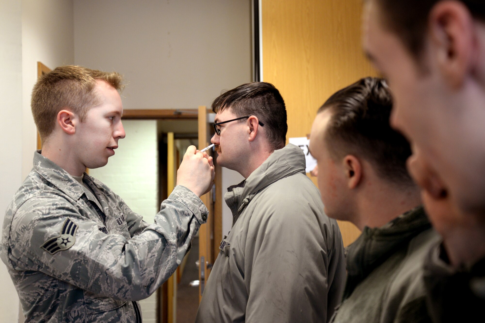 U.S. Air Force Senior Airman Eli Hedberg from the 48th Medical Group administers flu mists to Airmen Oct. 26, 2015, at the chapel on RAF Mildenhall, England, during the annual mass flu vaccine administration. Flu vaccines will be available 7 a.m. to 7 p.m. at the chapel Oct. 26, and at the Hardstand Fitness Center Oct. 27. (U.S. Air Force photo by Senior Airman Kate Thornton/Released)