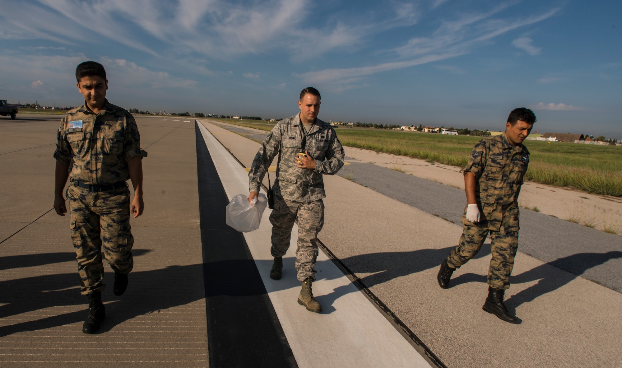 Senior Airman Eric Reding, 39th Maintenance Squadron munitions technician (center), walks with two Turkish air force airmen during a joint foreign object debris walk Oct. 8, 2015, Incirlik Air Base, Turkey. The U. S. and Turkish airmen come together annually to ensure the safety of the flight line and aircraft. (U.S Air Force photo by Staff Sgt. Eboni Reams/Released)