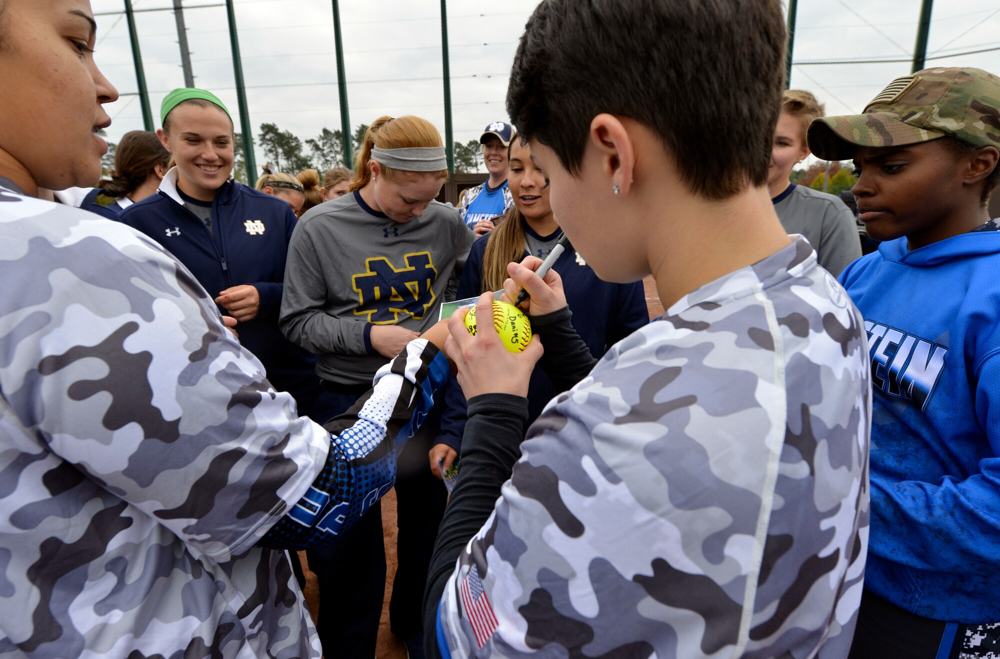 A Ramstein Air Base Lady Rams player autographs a softball for members of the University of Notre Dame softball team after a scrimmage Oct. 21, 2015, at Ramstein Air Base, Germany. The Lady Rams defeated Notre Dame by a score of 11-7. In addition to the scrimmage, the Notre Dame softball team held softball instructional clinics as part of their 10-day European tour. (U.S. Air Force photo/Staff Sgt. Sharida Jackson)
