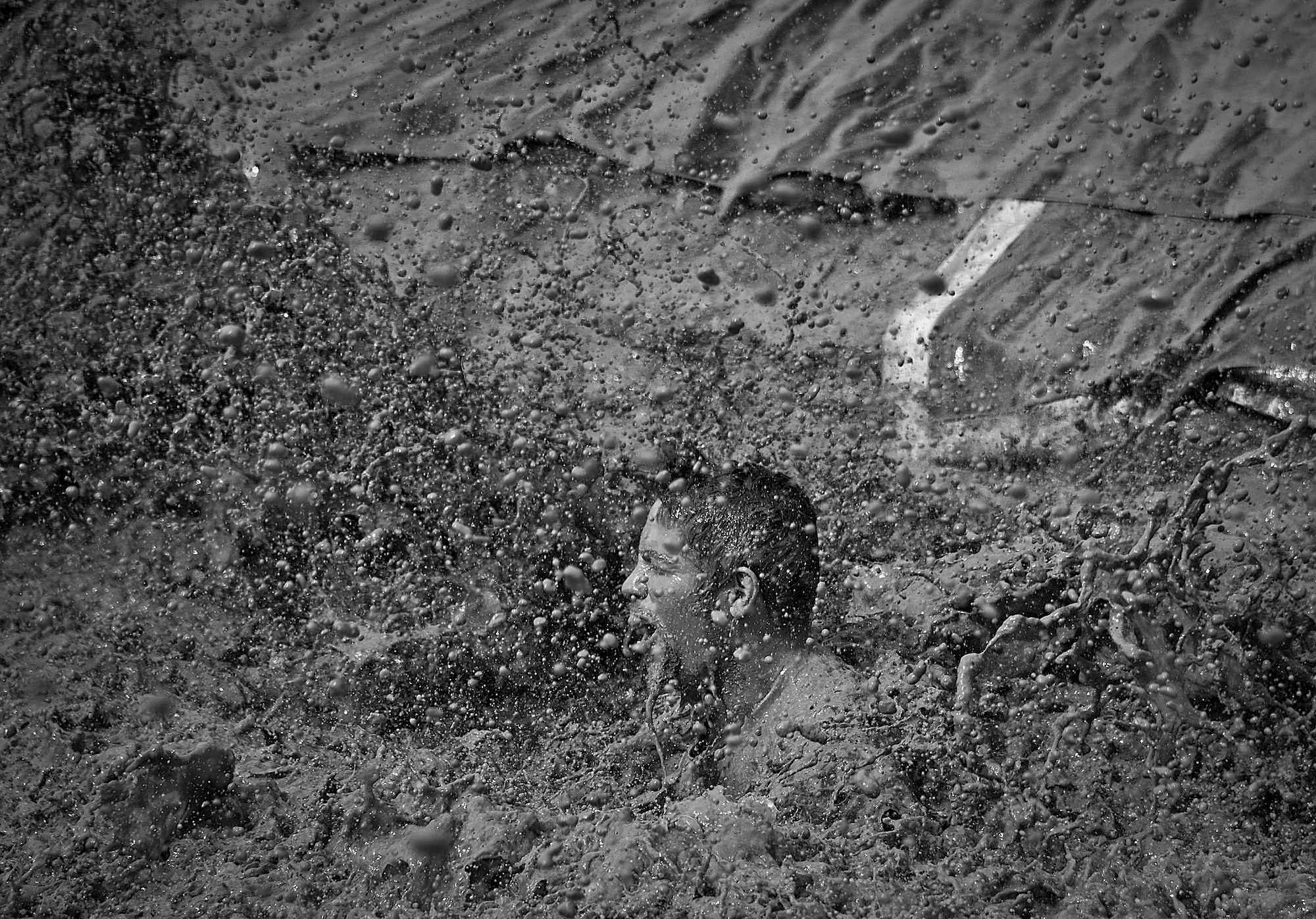 A competitor is enveloped by muddy water as he reaches the finish line via “mudslide” at the Pensacola Mud Run Oct 24. Active duty and reserve service members from many local military bases came out to get dirty in the five-mile, 20-obstacle challenge.  (U.S. Air Force photo/Tech. Sgt. Sam King)