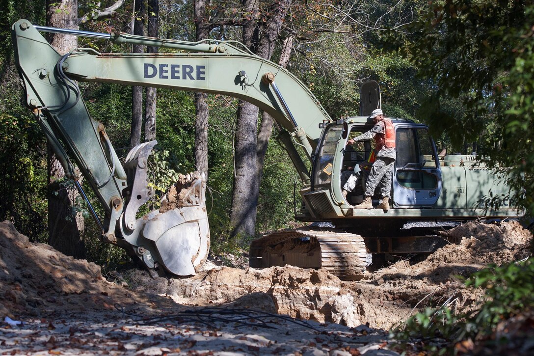 South Carolina Army National Guardsmen operate a back hoe to replace a washed out culvert in Gilbert, S.C., Oct. 24, 2015. The guardsmen are engineers assigned to the 1221st Engineering Company and 125th Multi Role Bridge Company. Soldiers with the South Carolina Army National Guard provided direct support for flood recovery and emergency road repairs as a result of the recent floods. South Carolina Army National Guard photo by Sgt. Brian Calhoun