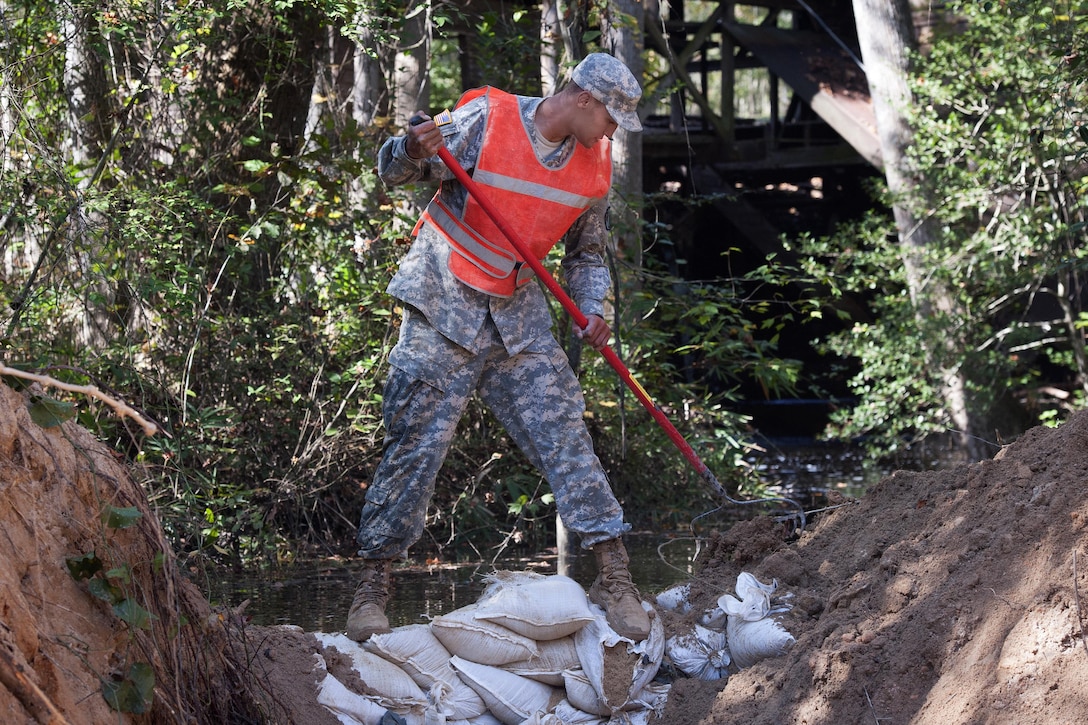 South Carolina Army National Guard Sgt. Chase Gambill uses a rake to move dirt around sand bags to temporarily stop the flow of water  in Gilbert, S.C., Oct. 24, 2015. Gambill is assigned to the 124th Engineering Company. South Carolina Army National Guard photo by Sgt. Brian Calhoun