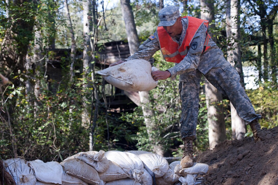 South Carolina Army National Guard Sgt. Chase Gambill places sand bags to temporarily stop the flow of water as engineers work to replace a washed out culvert in Gilbert, S.C., Oct. 24, 2015. Gambill is assigned to the 124th Engineering Company. South Carolina Army National Guard photo by Sgt. Brian Calhoun