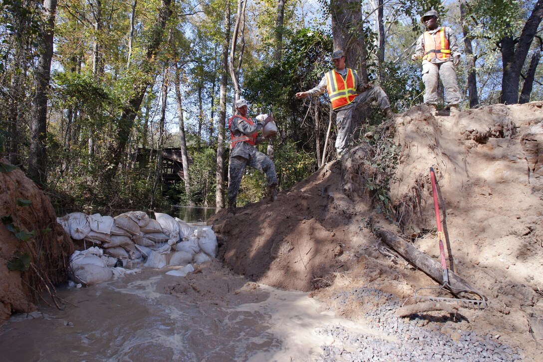 South Carolina Army National Guardsmen place sand bags to temporarily stop the flow of water as a team of engineers works to replace a washed out culvert on a Lexington County road in Gilbert, S.C., Oct. 24, 2015. South Carolina Army National Guard photo by Sgt. Brian Calhoun