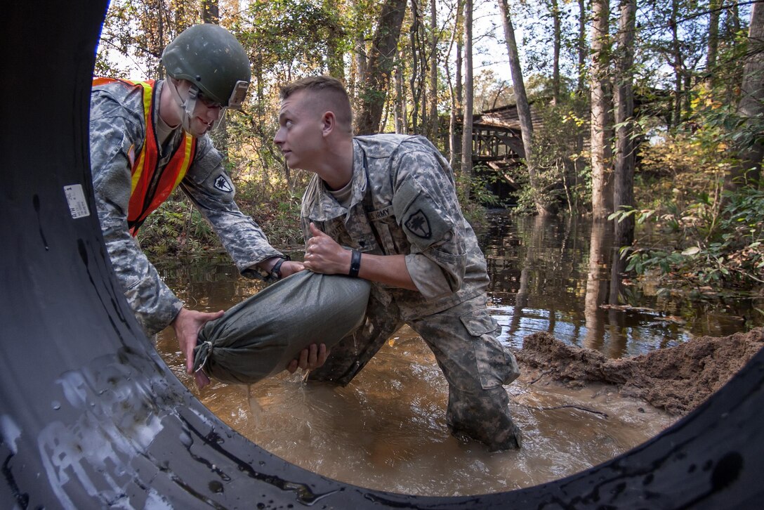 South Carolina Army National Guard 1st Lt. Benjamin Sternemann, left, and Spc. Connor Ulyatt secure a section of culvert pipe with sand bags as a team of engineers work to replace a washed out culvert on a Lexington County road in Gilbert, S.C., Oct. 24, 2015. Sternemann and Ulyatt are assigned to the 1221st Engineering Company. South Carolina Army National Guard photo by Sgt. Brian Calhoun