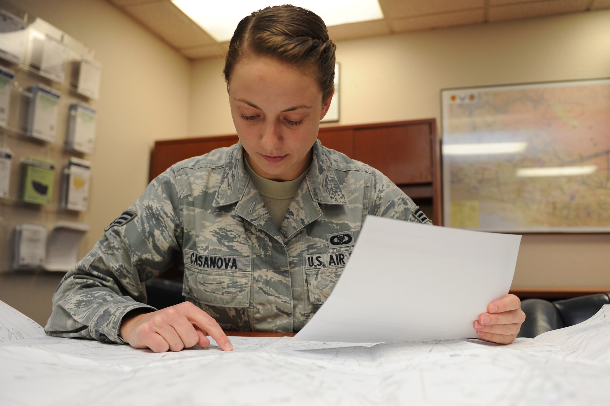 Senior Airman Monica Casanova, 56th Operations Support Squadron airfield management shift lead, references a map against a flight plan at the Luke Air Force Base airfield management office Oct 13 2015. Airfield managers log and keep pilot flight plans to have in case of emergency.