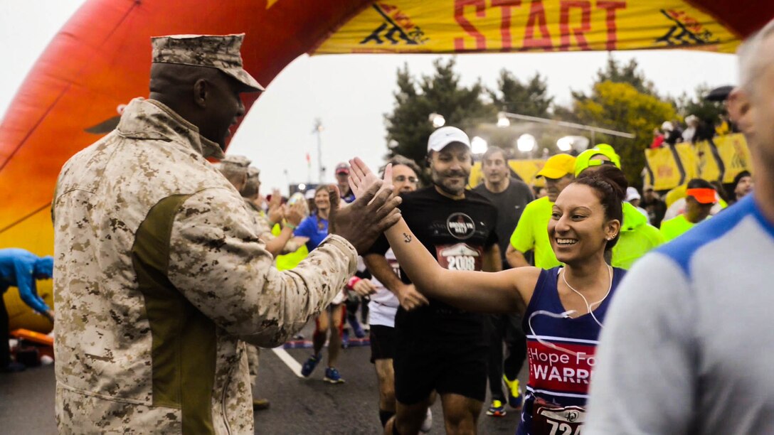 A Marine holds out his hands for high-fives for runners Oct. 25, 2015 at the 40th Marine Corps Marathon hosted in Washington and Arlington, Va. More than 30,000 participates started the race and more than 23,000 made it across the finish line.