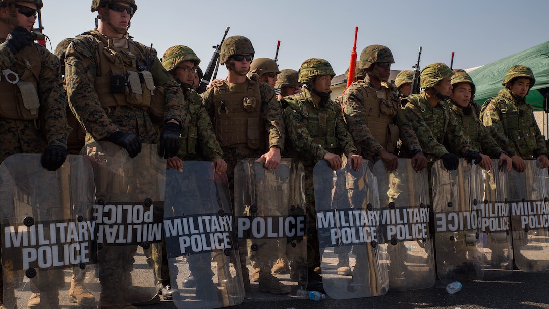 Marines and Japan Ground Self-Defense Force soldiers take a stance after a simulated riot control situation during Exercise Guard and Protect at Marine Corps Air Station Iwakuni, Japan, Oct. 20-23, 2015. Marines and JGSDF soldiers were challenged with real world situations such as riot control, armed intruder response and vehicle searches to prepare in case the air station has to take a defense posture.