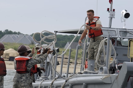 Pvt. 2 Seth Thorndell Rutter, 1098th Transportation Detachment (Medium Boat), throws a line from a Landing Craft Mechanized watercraft (LCM) to another Soldier to secure it for unloading operations at Fort Story during Terminal Warrior 2015. The Logistics-Over-the-Shore (LOTS) exercise took place in the Hampton Roads area of Virginia from mid July through mid August and included Reserve, National Guard and Active Duty units focused on cohesion and sharpening proficiency in basic LOTS skills as part of the Total Army Concept. 