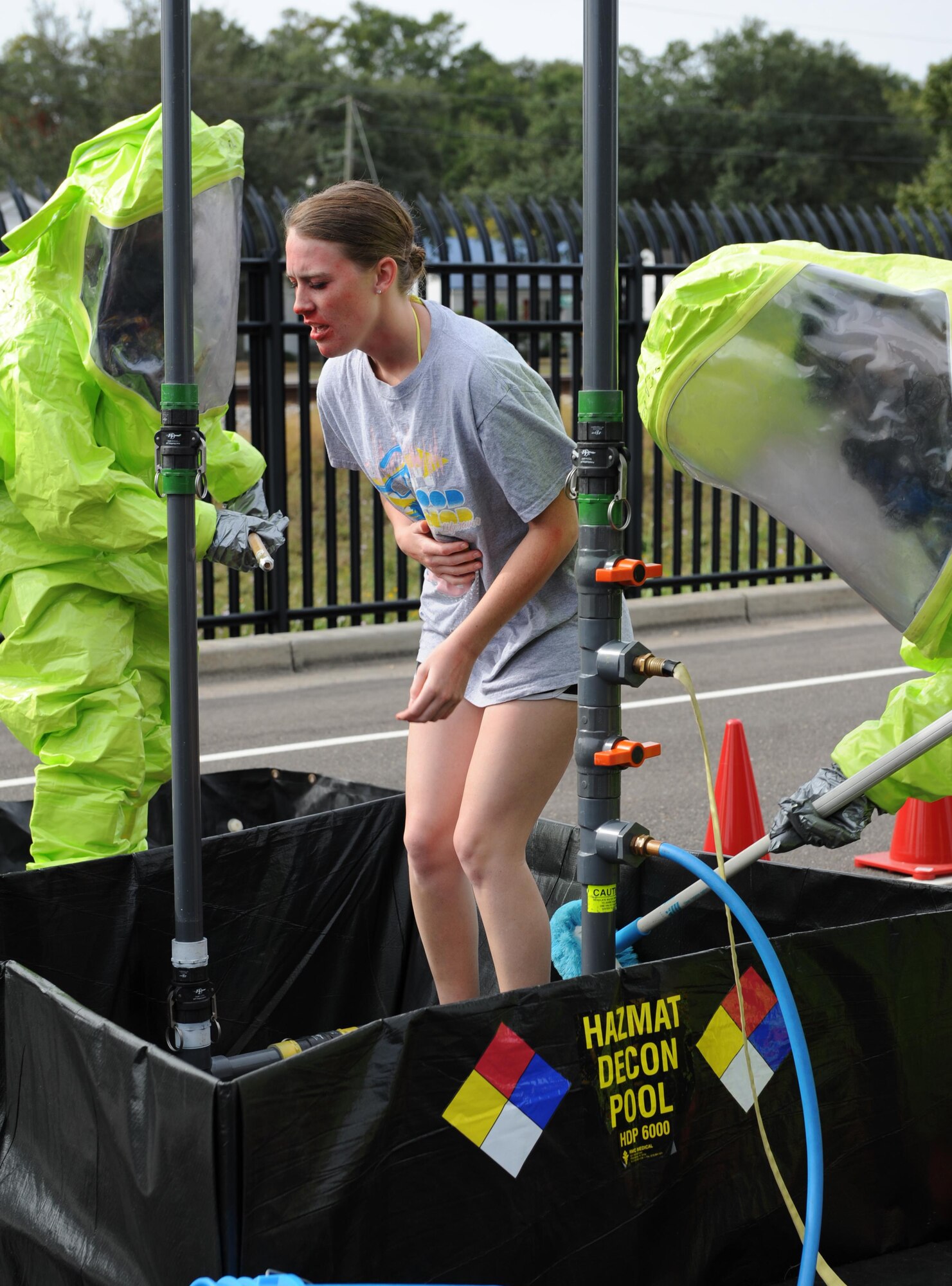 Keesler Firefighters follow decontamination procedures on Senior Airman Mikayla Dunne, 81st Dental Squadron dental technician, as she portrays a “victim” who was contaminated during a Chemical, Biological, Radiological and Nuclear exercise scenario, Oct. 22, 2015, Keesler Air Force Base, Miss. The Force Protection Condition exercise scenario included an intruder simulating releasing gas to cause a mass casualty event. Airmen who were returning from physical training simulated receiving skin, eye and lung burns from exposure to the chemical. (U.S. Air Force photo by Kemberly Groue)