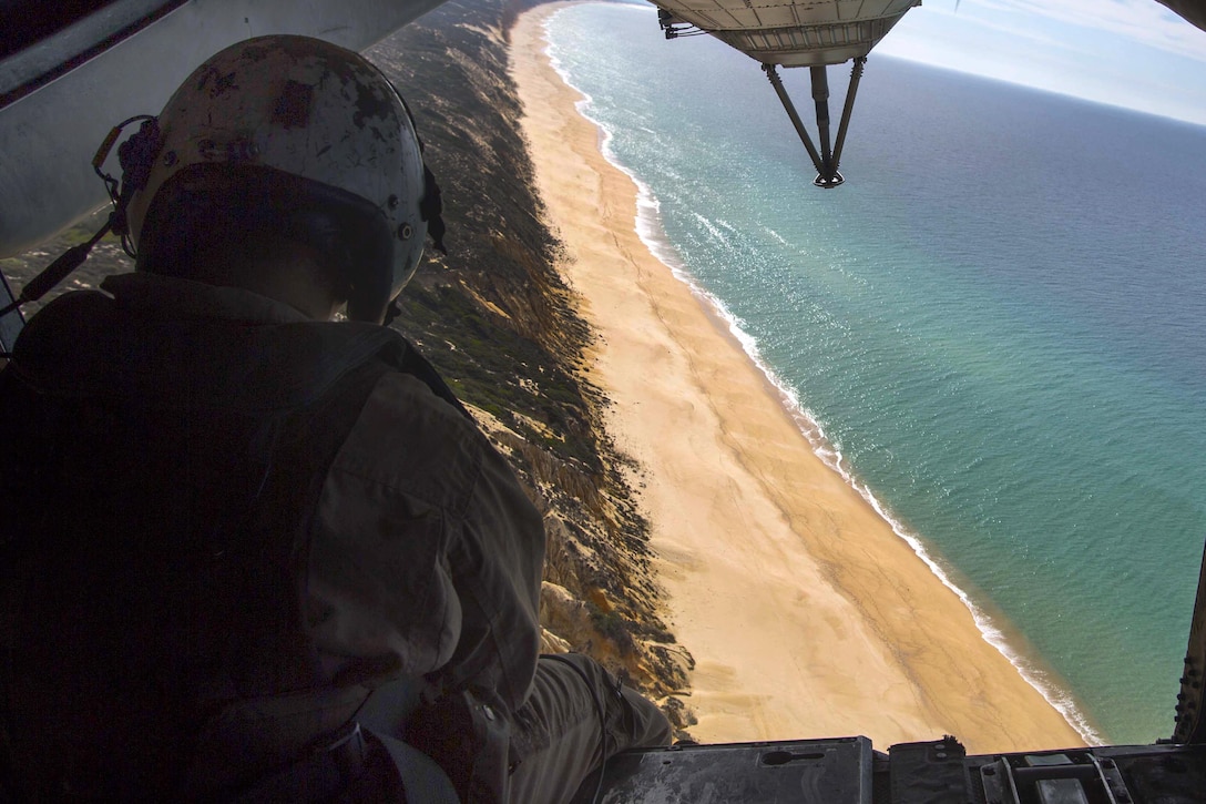U.S. Marine Corps Cpl. Nicholas Chieu sits on the ramp of a crew chief aboard a CH-53E Sea Stallion helicopter while flying to participate in a combined helicopter assault training near Pinheiro Da Cruz Beach, Portugal, Oct. 21, 2015, during exercise Trident Juncture 15. Chieu is a crew chief assigned to the 26th Marine Expeditionary Unit, embarked aboard the amphibious transport dock ship USS Arlington. U.S. Marine Corps photo by Sgt. Austin Long 