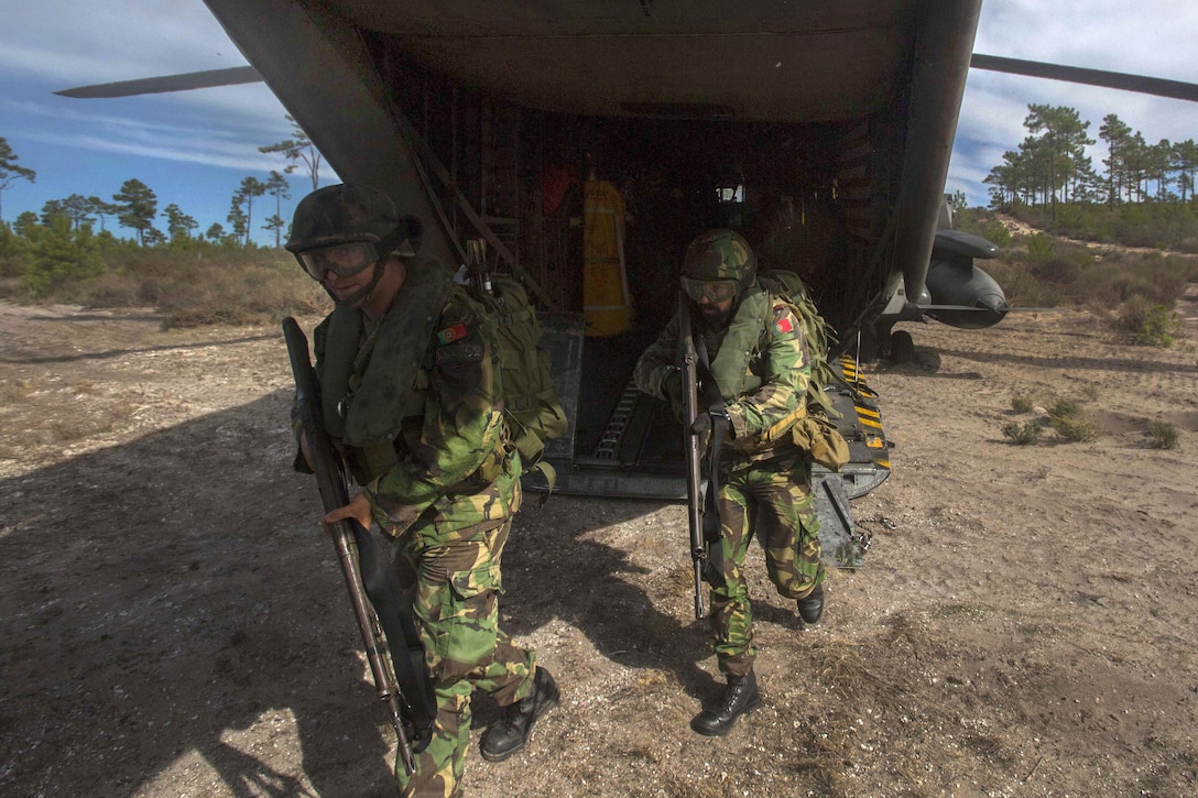 Portuguese Marines unload from a U.S. Marine Corps CH-53E Sea Stallion helicopter after landing to participate in a combined helicopter assault training near Pinheiro Da Cruz Beach, Portugal, Oct. 21, 2015, during exercise Trident Juncture 15. U.S. Marine Corps photo by Sgt. Austin Long