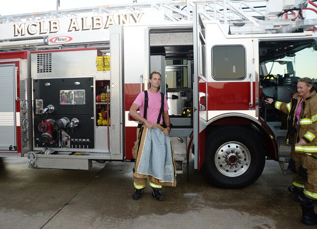 Firefighter/paramedic Ron Hedgecoke, Fire Department, Marine Corps Logistics Base Albany, suits up in response to a call during a simulated drill on the installation, recently. In keeping with the traditional October uniform-of-the-day, Hedgecoke wore a pink T-shirt as a symbol of the department’s efforts to heighten awareness and to show support in the fight against breast cancer.
