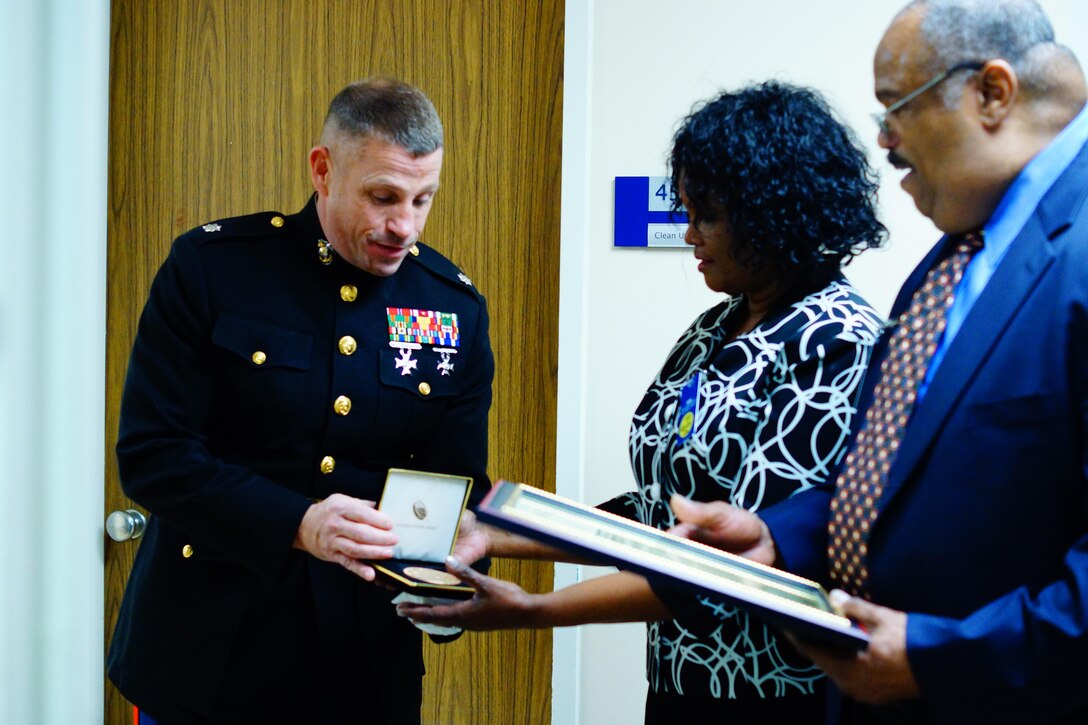 Lt. Col. Michael F. Arnone (left), Inspector-Instructor 1st Battalion, 24th Marine Regiment, 4th Marine Division, presents the Congressional Gold Medal to Dr. James J. Neal and Therian Neal Brown, the son and goddaughter of Montford Point Marine James Neal, at Harper University Hospital in Detroit, Mich. Oct. 23, 2015. The Congressional Gold Medal is the highest civilian honor bestowed by Congress for distinguished achievement.  The President of the United States, President Barack Obama, signed into law the legislation to award the Congressional Gold Medal to Montford Point Marines on Nov. 23, 2011.  This award recognizes Montford Point Marines' contributions to the Marine Corps and the United States of America from 1942 to 1949, when approximately 20,000 African American recruits were trained at a segregated base called Camp Montford Point. 