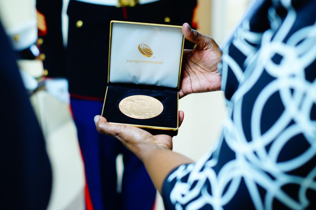 Therian Neal Brown, goddaughter of Montford Point Marine Mr. James Neal, looks proudly at the Congressional Gold Medal presented Oct. 23, 2015, to her and her godbrother Dr. James J. Neal, by Lt. Col. Michael F. Arnone, Inspector-Instructor 1st Battalion, 24th Marine Regiment, 4th Marine Division. Brown and Dr. Neal accepted the medal on behalf of their father at Harper University Hospital in Detroit, Mich. The Congressional Gold Medal is the highest civilian honor bestowed by Congress for distinguished achievement.  The President of the United States, President Barack Obama signed into law, the legislation to award the Congressional Gold Medal to Montford Point Marines on Nov. 23, 2011.  This award recognizes Montford Point Marines' contributions to the Marine Corps and the United States of America from 1942 to 1949, when approximately 20,000 African American recruits were trained at a segregated base called Camp Montford Point. (U.S. Marine Corps photo by Gunnery Sgt. David Flores) (U.S. Marine Corps photo by Gunnery Sgt. David Flores)