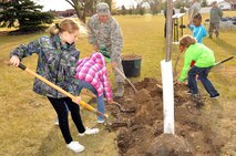 Col. Anthony Hernandez, 319th Mission Support Group commander, along with several Grand Forks Air Force Base children, plants a tree to commemorate Arbor Day during a ceremony held here Oct. 26, 2015. Grand Forks Air Force Base, North Dakota, was awarded the Tree City USA distinction for 2014. Tree City USA is a program through the Arbor Day Foundation that recognizes communities across the country that have a tree board or department (responsible for caring for all the trees on the community’s property), a tree care ordinance, a community forestry program with an annual budget of at least $2 per capita, as well as an Arbor Day Observance or Proclamation. (U.S. Air Force photo/Staff Sgt. Susan L. Davis)