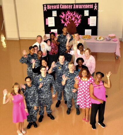 Naval Health Clinic Charleston staff members form up in the shape of a pink ribbon to take a group photo in support of breast cancer survivors, to remember those lost to the disease and to support the progress being made to defeat breast cancer. NHCC hosted a Breast Cancer Awareness Event Oct. 13 at the clinic, where staff members were offered breast cancer prevention information and a healthy fruit snack. NHCC civilian staff members were invited to wear pink and service members were given pink ribbons to wear on their ID badges. The pink ribbon lapel pin is a powerful symbol increasing breast cancer awareness. (U.S. Navy photo/Kris Patterson)