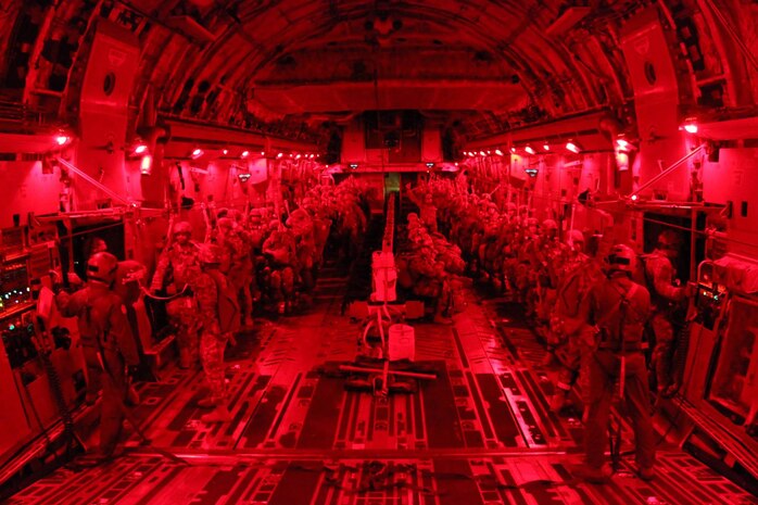 Army jump masters with the 3rd Squadron, 73rd Cavalry, 1st Brigade Combat Team, 82nd Airborne Division, conduct paratrooper door checks during a night tactical combat jump aboard a C-17 Globemaster III from the 437th Airlift Wing, while flying over Fort Bragg, North Carolina, Oct. 20, 2015. The purpose of the jump was to practice exiting the aircraft with cavalrymen and a full combat equipment load to secure a drop zone. The interior lights are red to remain tactical and assist the paratroopers adjust their eyes upon exiting the aircraft. (U.S. Army photo/Sgt. Chad Haling)