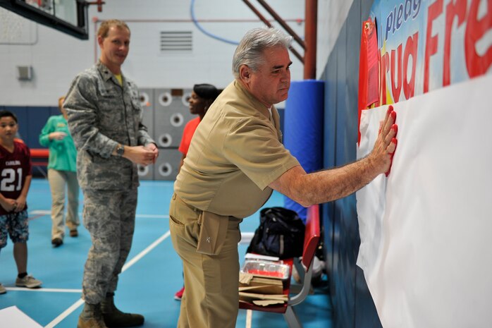 (Right) U.S. Navy Capt. Timothy Sparks, 628th Air Base Wing vice commander, and Lt. Col. Ralph Thomas, 628th Mission Support Group deputy commander, begin the drug free living ceremony by leaving their hand prints and signatures during the Red Ribbon Week kickoff event at Joint Base Charleston - Air Base, S.C., Oct. 23, 2015. More than 20 children took the pledge to be drug free during this year's event. (U.S. Air Force photo/Tech. Sgt. Renae Pittman)