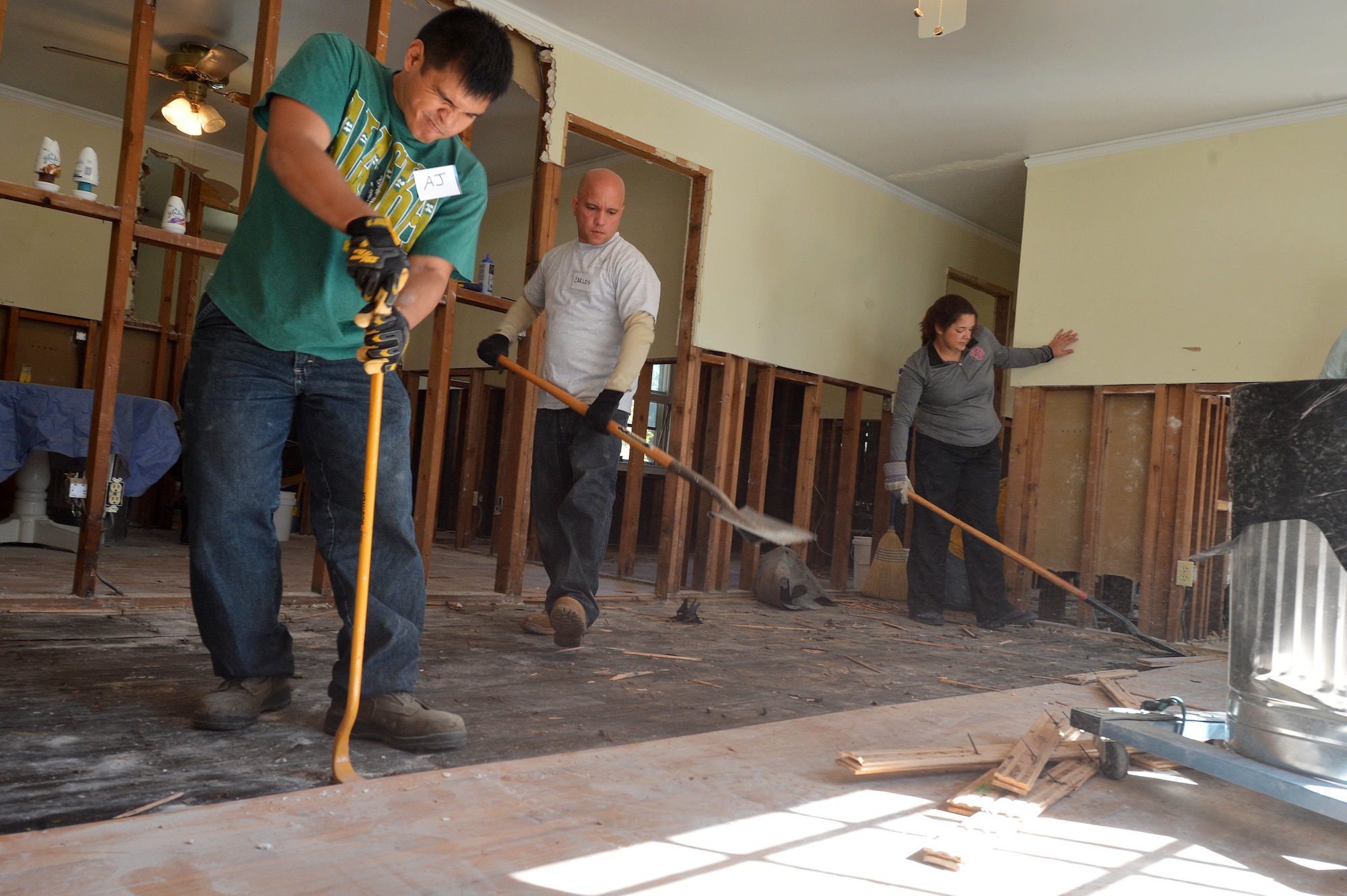 (Left) Two 20th Civil Engineer Squadron Airmen and a disaster relief volunteer tear up wood floors at a home affected by the flood in Sumter, S.C., Oct. 19, 2015. Organizations on Shaw Air Force Base, S.C., created multiple groups of more than 85 volunteers to assist in the disaster relief efforts for the Sumter community. (U.S. Air Force photo by Senior Airman Diana M. Cossaboom/Released)