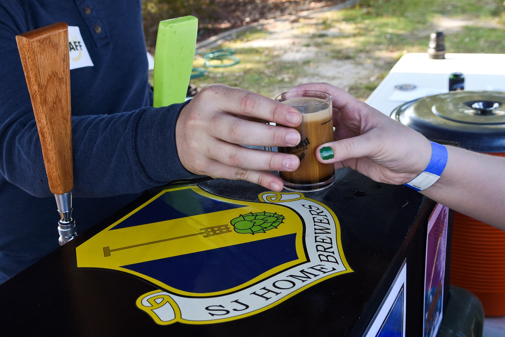 A member of Team Seymour accepts a sample of beer brewed by the SJ Home Brew Club, Oct. 24, 2015, at Seymour Johnson Air Force Base, North Carolina, during Oktobrewfest. The club, which organized the event, is one of many born from the ‘Make it Better’ initiative. (U.S. Air Force photo/Senior Airman Aaron J. Jenne)
