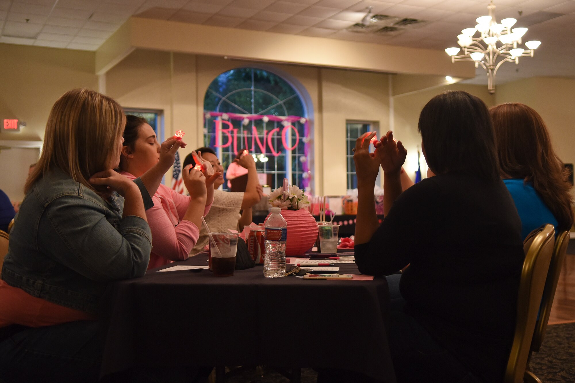 Members of the Officers and Civilian Spouses Club and the Enlisted Spouses Club raise glowing pink rings in a pledge to get tested for breast cancer, Oct. 23, 2015, at Seymour Johnson Air Force Base, North Carolina, during a Bunco for Breast Cancer event. The fundraiser brought in more than $650 for the Combined Federal Campaign. (U.S. Air Force photo/Senior Airman Aaron J. Jenne)