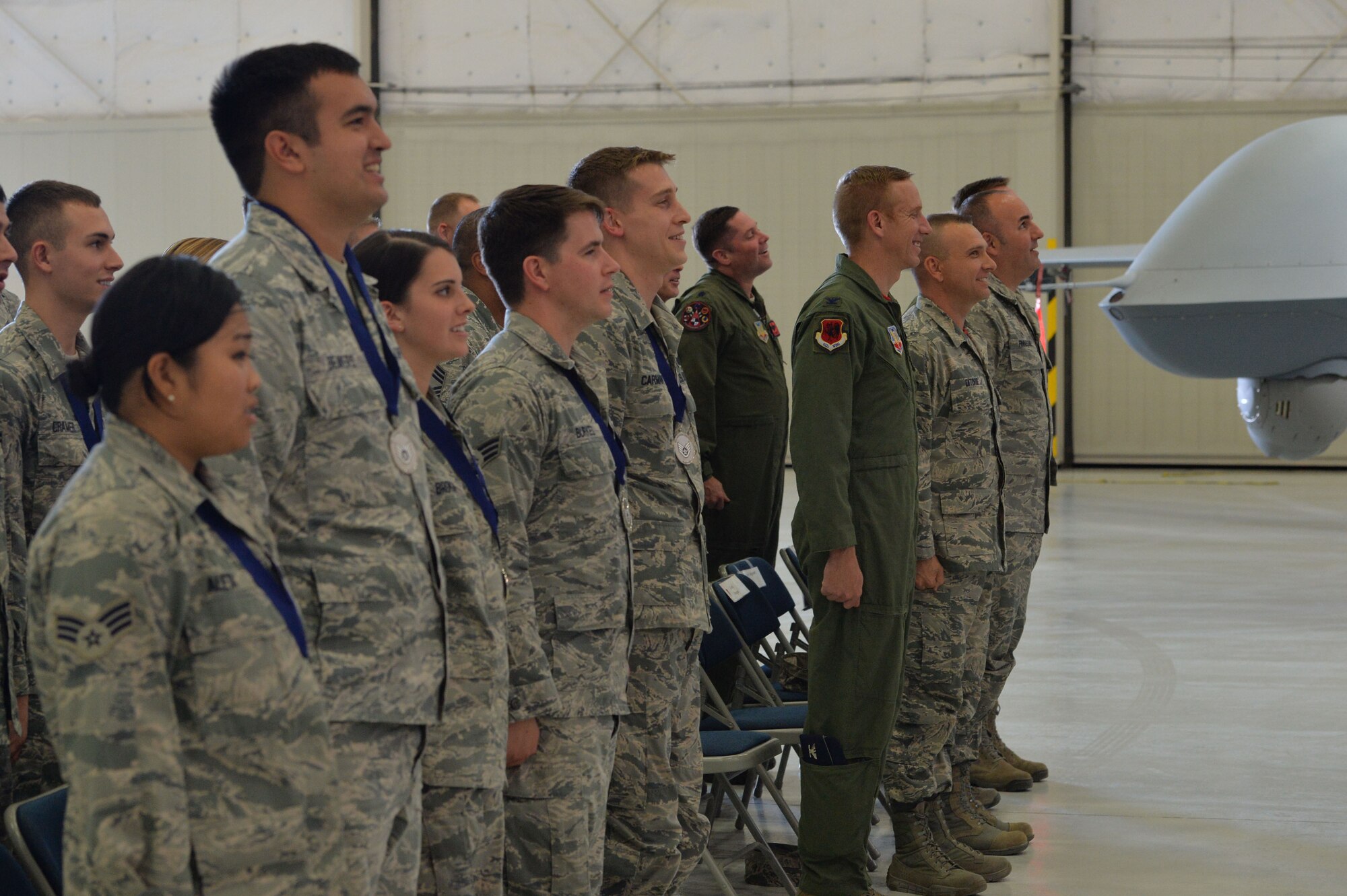 Team Creech staff sergeant selects and 432nd Wing/432nd Air Expeditionary Wing leadership stand during the playing of the Air Force song after the NCO Induction Ceremony at Creech Air Force Base, Nev., Oct. 23, 2015. Approximately 50 inductees were honored for their promotion and received important leadership advice as they prepare to transition to the NCO ranks. This was the first time Team Creech Airmen were recognized with a formal NCO induction ceremony. (U.S. Air Force photo by Senior Airman Adarius Petty)