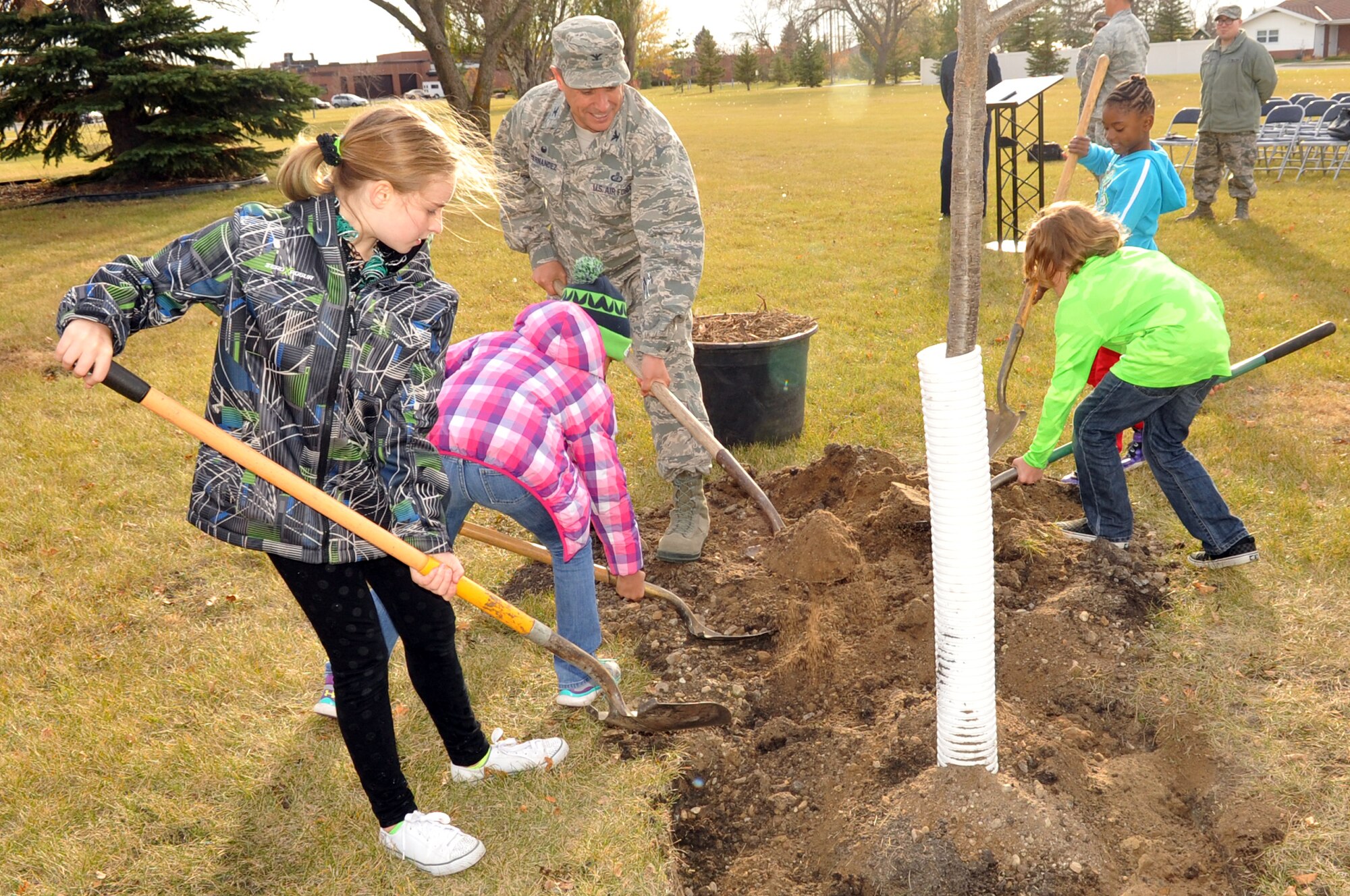 Col. Anthony Hernandez, 319th Mission Support Group commander, along with several Grand Forks Air Force Base children, plants a tree to commemorate Arbor Day during a ceremony held here Oct. 26, 2015. Grand Forks Air Force Base, North Dakota, was awarded the Tree City USA distinction for 2014. Tree City USA is a program through the Arbor Day Foundation that recognizes communities across the country that have a tree board or department (responsible for caring for all the trees on the community’s property), a tree care ordinance, a community forestry program with an annual budget of at least $2 per capita, as well as an Arbor Day Observance or Proclamation. (U.S. Air Force photo/Staff Sgt. Susan L. Davis)