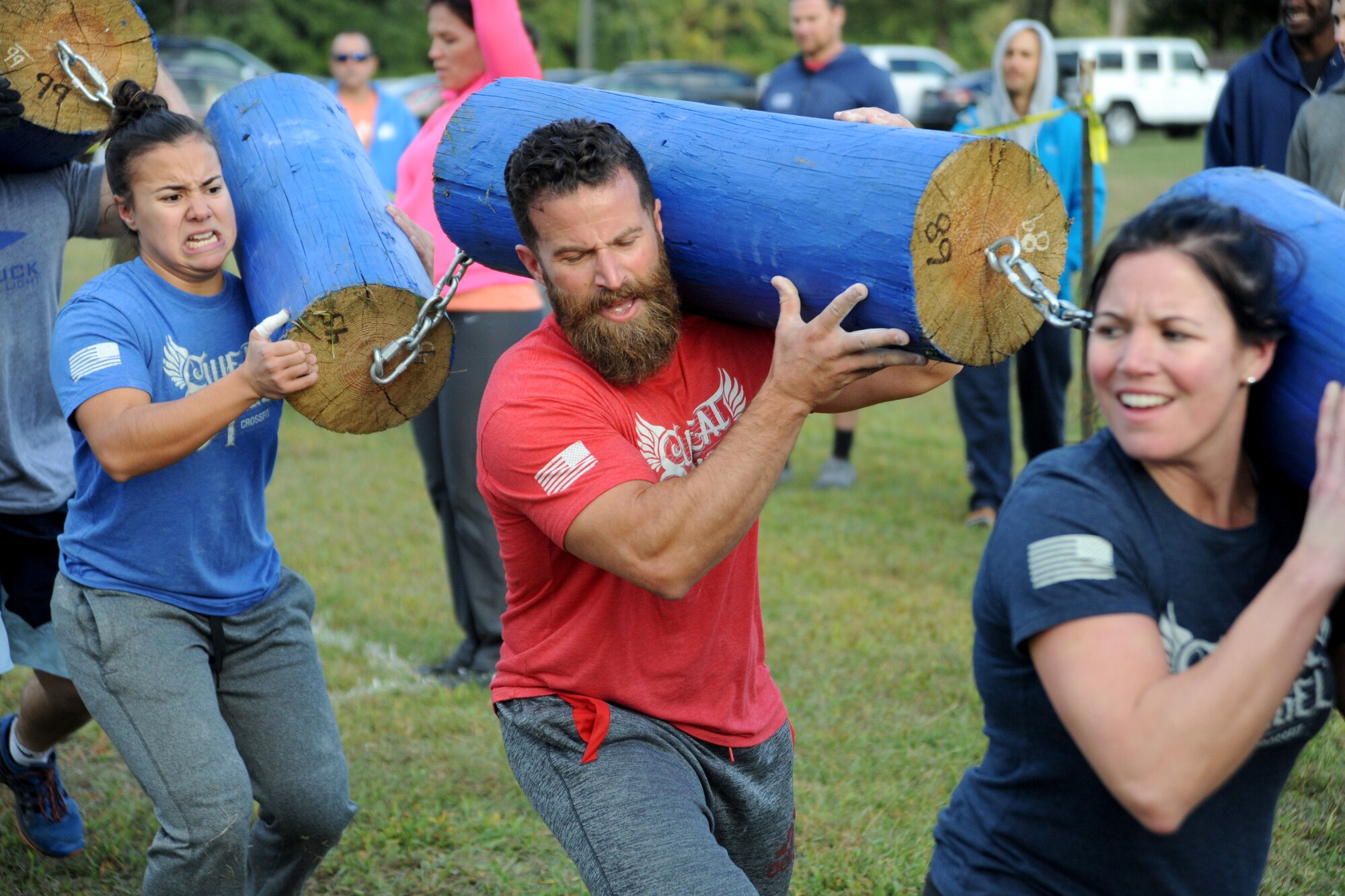 Airman 1st Class Karla Montes, 436th Dental Squadron dental assistant, left, carries a log during the group challenge at the Eastern Shore Affiliate Challenge Oct. 17, 2015, in Georgetown, Del. Mike and Christen Georgules, middle and right, owners and coaches at Crossfit Sweat Angel, train many military clients. (U.S. Air Force photo/Staff Sgt. Elizabeth Morris)