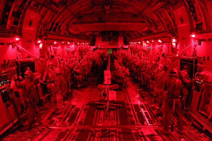 Army jump masters with the 3rd Squadron, 73rd Cavalry, 1st Brigade Combat Team, 82nd Airborne Division, conduct paratrooper door checks during a night tactical combat jump aboard a C-17 Globemaster III from the 437th Airlift Wing, while flying over Fort Bragg, North Carolina, Oct. 20, 2015. The purpose of the jump was to practice exiting the aircraft with cavalrymen and a full combat equipment load to secure a drop zone. The interior lights are red to remain tactical and assist the paratroopers adjust their eyes upon exiting the aircraft. (U.S. Army photo/Sgt. Chad Haling)