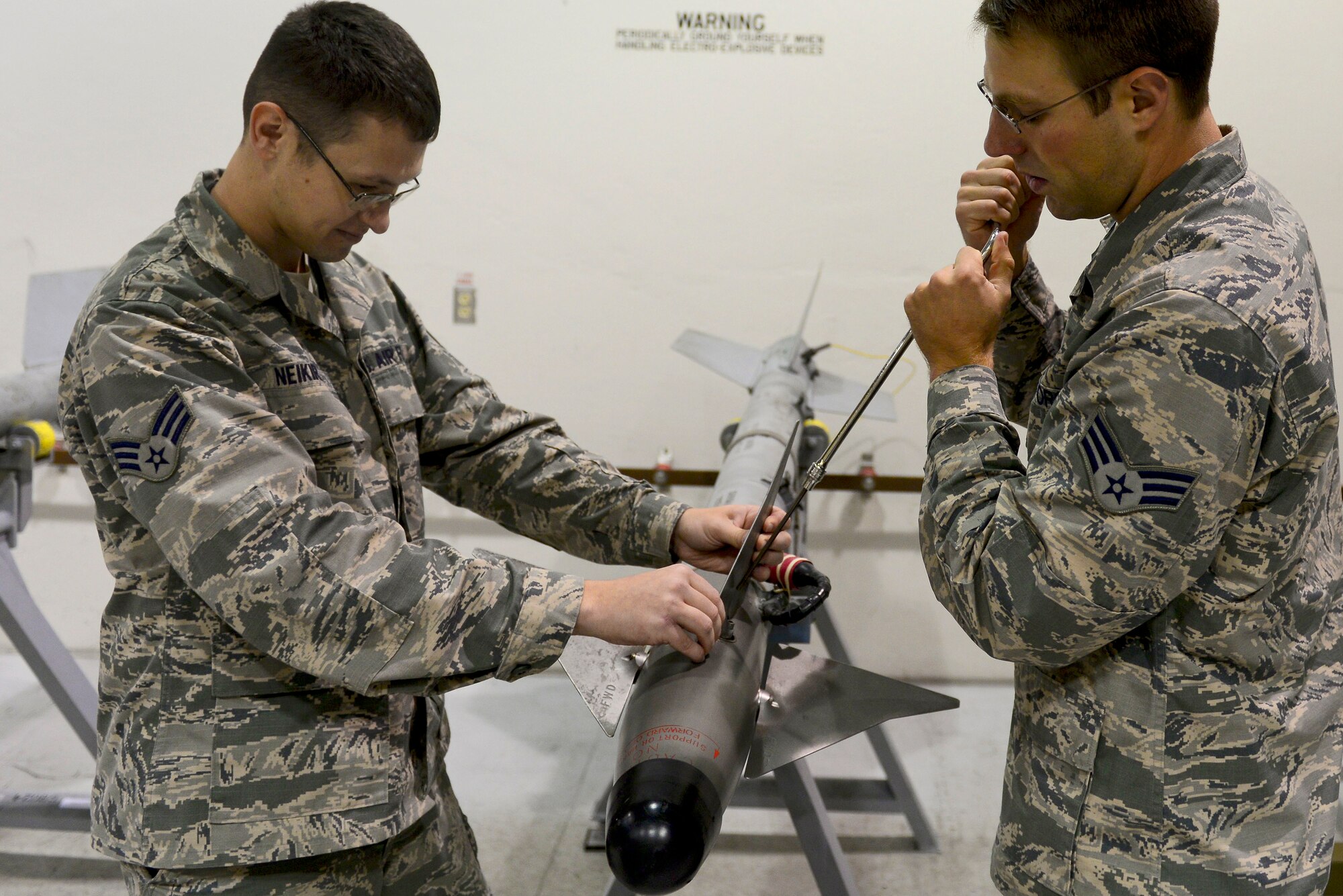 U.S. Air Force Senior Airmen Zachary Neikark and Garrett Peak, 1st Maintenance Squadron ammunition technicians, disassemble wings of a training missile at Langley Air Force Base, Va., Oct. 19, 2015. Taking apart the Captive Air Training Missile 9m gives Airmen the opportunity to show they can examine and follow the proper inspecting procedures. (U.S. Air Force photo by Airman 1st Class Derek Seifert/ Released)